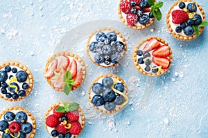 Healthy summer pastry dessert. Berry tartlets or cake with cream cheese top view.