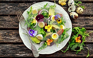 Healthy summer salad with quail eggs, avocado, pecans, wild rocket, red onion and edible viola flowers.