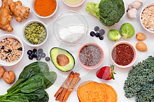 Healthy super food ingredients. Overhead view table scene on a white marble background.