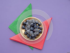 Healthy superfood blueberries on colourful background with paper napkins, serviettes and gold plate.