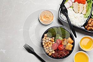 Healthy takeaway meals served with sauce and juice on light grey marble table, flat lay. Space for text