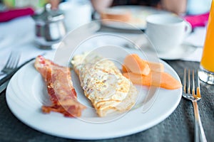 Healthy tasty american breakfast with omlette and bacon on table in cafe