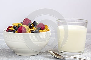 Healthy tasty breakfast: bowl with corn flakes and berries and glass of milk