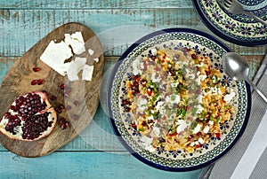 Healthy and so tasty bulgursalat with fruits, chesee, mango, pepper, pomegranate fruit, apricot in a blue plate.