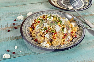 Healthy and so tasty bulgursalat with fruits, chesee, mango, pepper, pomegranate fruit, apricot in a blue plate.