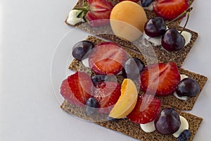 Healthy and tasty toasts with curd cheese, fruits and berries on a white background