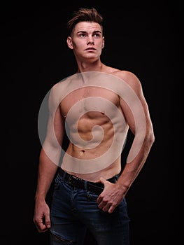 Healthy teenage guy shirtless on a black background. Sporty young men. Muscle building concept.