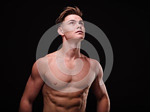 Healthy teenage guy shirtless on a black background. Sporty young men. Muscle building concept.