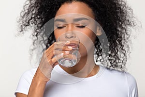 Healthy thirsty african woman drinking water isolated on white background