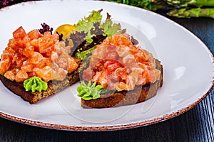 Healthy toasts with rye bread with salmon, avocado mousse, lettuce on white plate