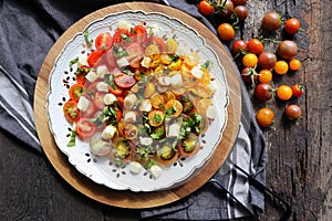 Healthy tomato Salad with cherry red and yellow tomatoes, topping balsamic sauce and basil on white plate