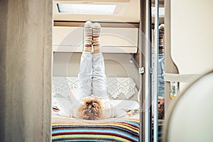 Healthy traveler woman doing stretching and workout exercises inside a campe van bedroom getting up the legs. Alternative van life