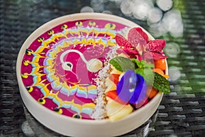Healthy tropical breakfast, smoothie bowl with tropical fruits, decorated with a pattern of colorful yogurt with