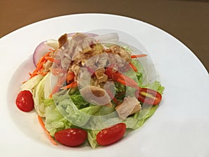 Healthy Tuna salad with lettuce tomato and light vinegar dressing in white plate on wooden table,stylist fusion food,focus-on-fore