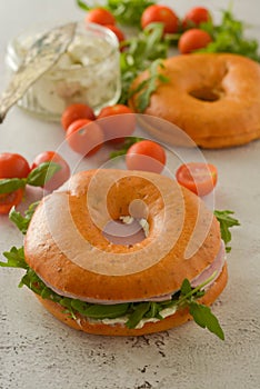 Healthy turkey ham sandwich on a bagel with greens and tomato. Breakfast