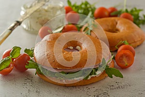 Healthy turkey ham sandwich on a bagel with greens and tomato. Breakfast