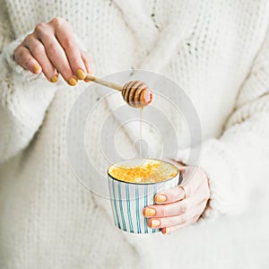 Healthy turmeric latte or golden milk with honey, square crop