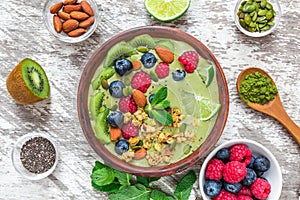 Healthy vegan breakfast. matcha green tea smoothie bowl with fresh fruits, berries, nuts, seeds and granola. top view