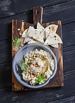 Healthy vegan cauliflower hummus and homemade tortilla on a dark rustic cutting board on a dark background.