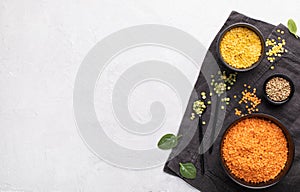 Healthy vegan food. Colorful lentil in black bowl on light gray background. Top view