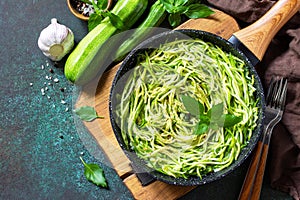 Healthy vegan food, low carb dish. Cooked zucchini noodles with basil and garlic in a cast iron pan