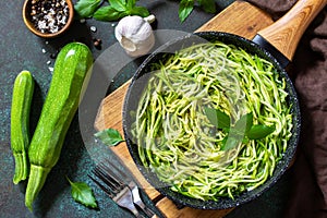 Healthy vegan food, low carb dish. Cooked zucchini noodles with basil and garlic in a cast iron pan