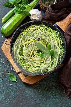 Healthy vegan food, low carb dish. Cooked zucchini noodles with basil and garlic in a cast iron pan