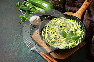 Healthy vegan food, low carb dish. Cooked zucchini noodles with basil and garlic in a cast iron pan