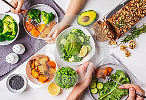 Healthy vegan food lunch, top view. Vegetarian dinner table, people eat healthy food. Salad, sweet potato, vegan cake, vegetables