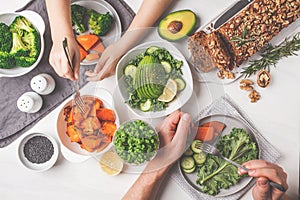 Healthy vegan food lunch, top view. Vegetarian dinner table, people eat healthy food. Salad, sweet potato, vegan cake, vegetables