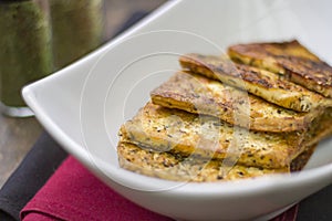 Healthy vegan fried tofu slices with seasonings on plate