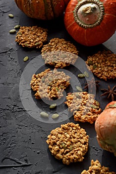 Healthy vegan gluten free food. Homemade pumpkin oatmeal breakfast cookies with seeds and turban squash on black background