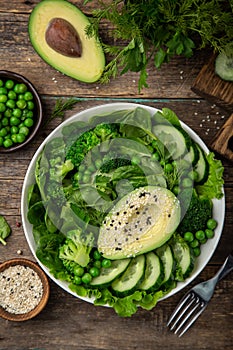 Healthy vegan green salad with avocado, broccoli, cucumber, green peas and spinach in white  bowl