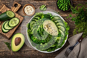 Healthy vegan green salad with avocado, broccoli, cucumber, green peas and spinach in white  bowl