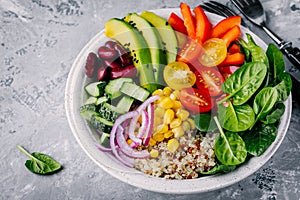 Healthy vegan lunch Buddha bowl. Avocado, quinoa, tomato, cucumber, red beans, spinach, red onion and red paprika vegetables salad