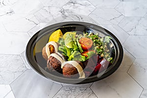 Healthy Vegan Take Away Falafel Bowl with Mung Bean Salad, Legume, Roasted Beet and Yellow Turmeric Hummus Tahini Sauce in Black