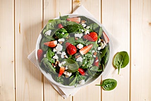 Healthy vegetable salad of fresh spinach, strawberries, feta cheese and almond on plate