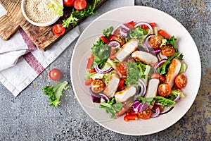 Healthy vegetable salad with grilled chicken breast, fresh lettuce, cherry tomatoes, red onion and pepper