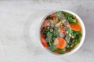 Healthy vegetable soup with kale and lentils, above on white marble