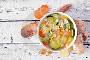 Healthy vegetable soup with turmeric and ginger. Top view table scene on white wood.