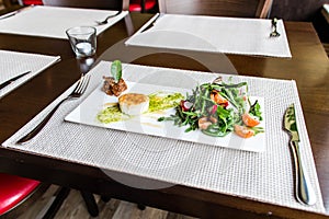 Healthy vegetable summer salad, fresh vegetables and dressing with grilled cheese flambe arranged on plate dinner table