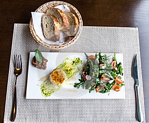 Healthy vegetable summer salad, fresh vegetables and dressing with grilled cheese flambe arranged on plate dinner table