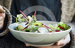 Healthy vegetables salad in bowl, woman with bowl and fork eating healthy salad, clean eating