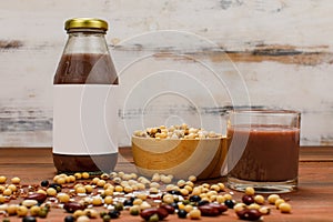 Healthy vegetarian beverage glass bottle and cup on kitchen table with ingredient bowl of soybean grain and brown rice