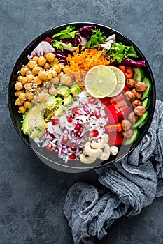 Healthy vegetarian Buddha bowl with fresh vegetable salad, rice, chickpea, avocado, sweet pepper, cucumber, carrot, pomegranate an