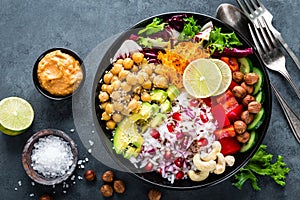 Healthy vegetarian Buddha bowl with fresh vegetable salad, rice, chickpea, avocado, sweet pepper, cucumber, carrot, pomegranate an