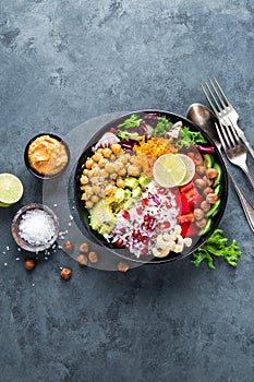 Healthy vegetarian Buddha bowl with fresh vegetable salad, rice, chickpea, avocado, sweet pepper, cucumber, carrot, pomegranate an