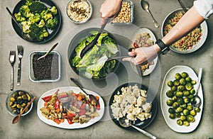 Healthy vegetarian dishes in plates and woman`s hands taking salad