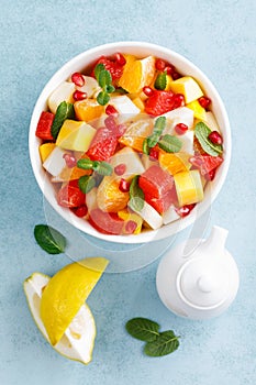 Healthy vegetarian fresh fruit salad with apple, pear, tangerine, grapefruit, mango, pomegranate and lemon juice. Top view