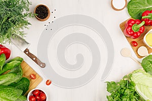 Healthy vegetarian ingredients for spring fresh green salad and kitchenware on white wood board, top view, copy space.